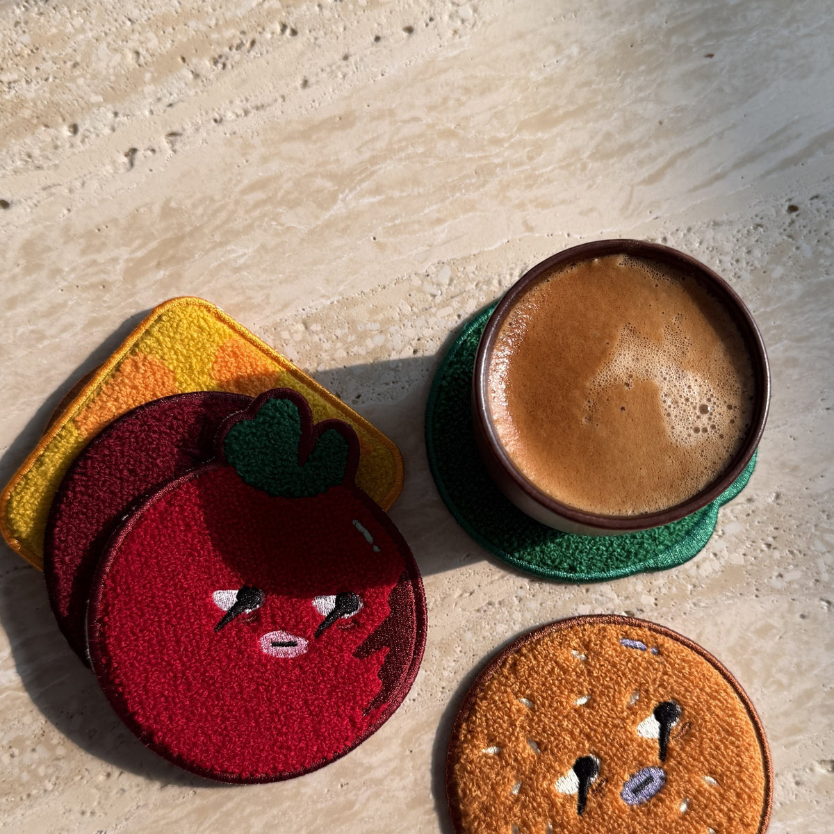 Daging Burger Coaster Stack — tomato and top bun coasters next to a cup of coffee