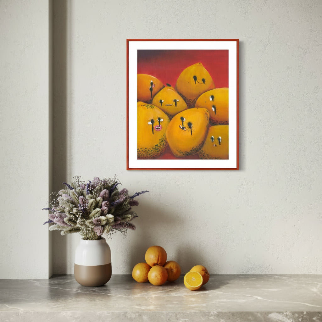 Framed artwork of lemons with faces on a wall above a table with lemons and a vase.